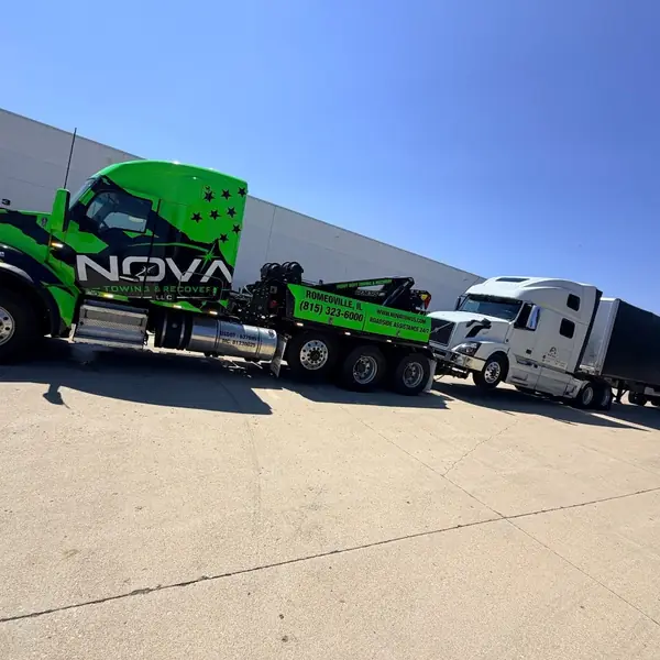 NOVA wrecker towing a Volvo semi from a warehouse lot